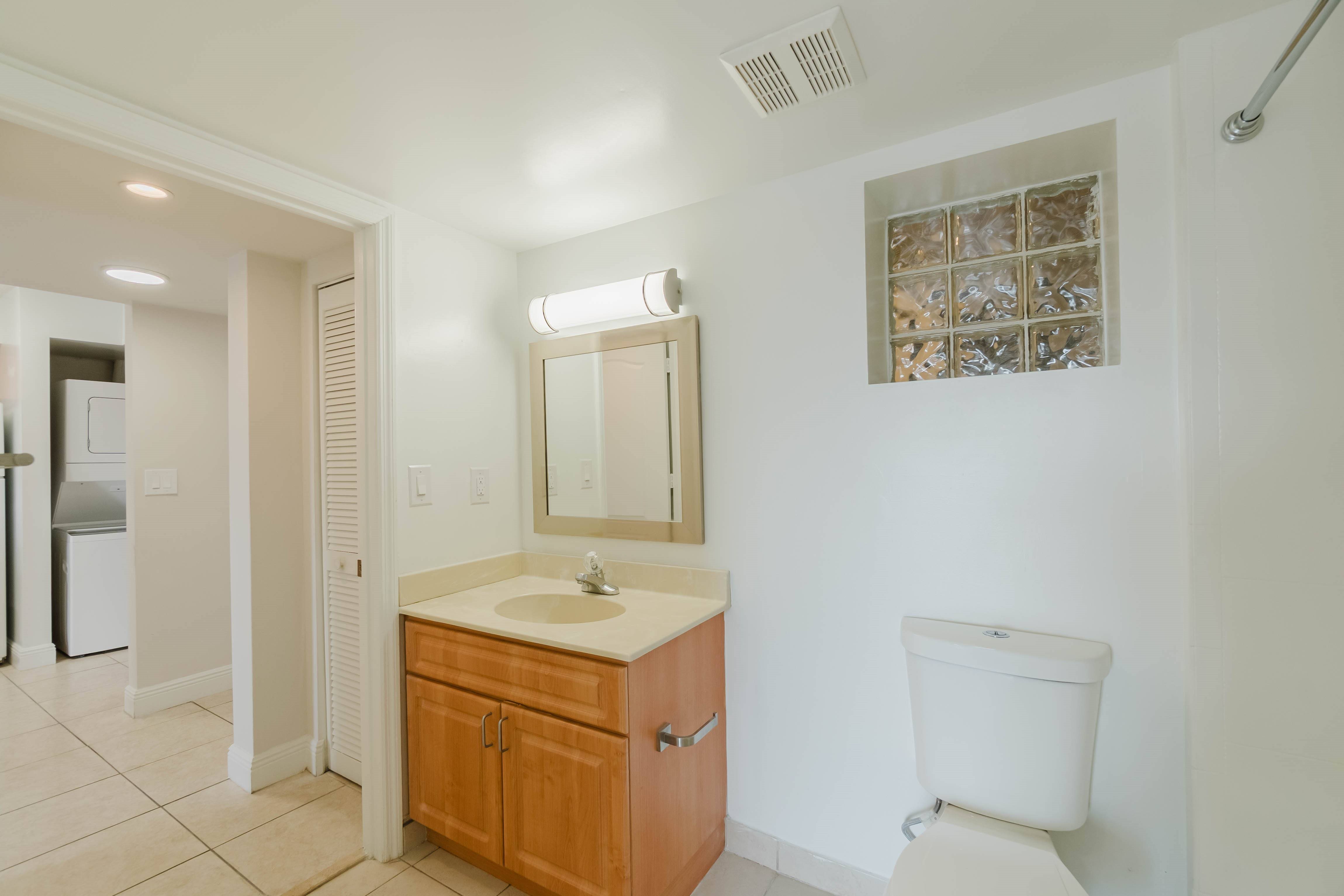 A bathroom with a toilet, sink, and mirror.
